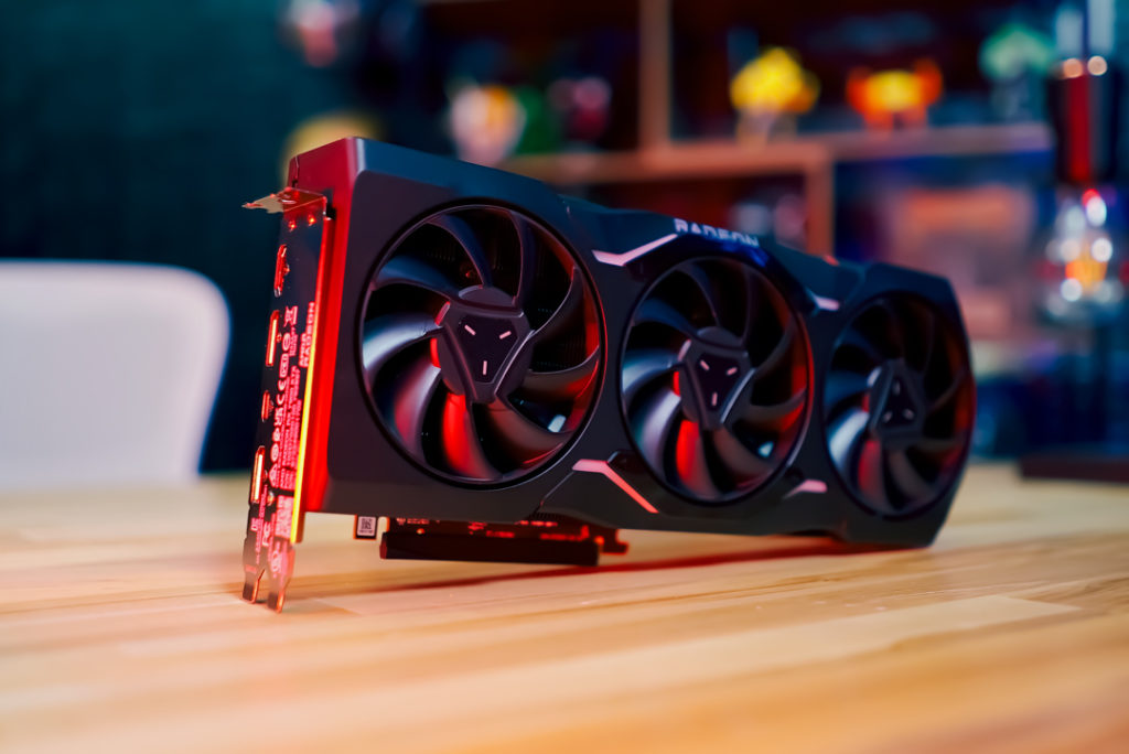 AMD Radeon RX 7900 XTX graphics card with three built in fans laying horizontally on a wooden table.