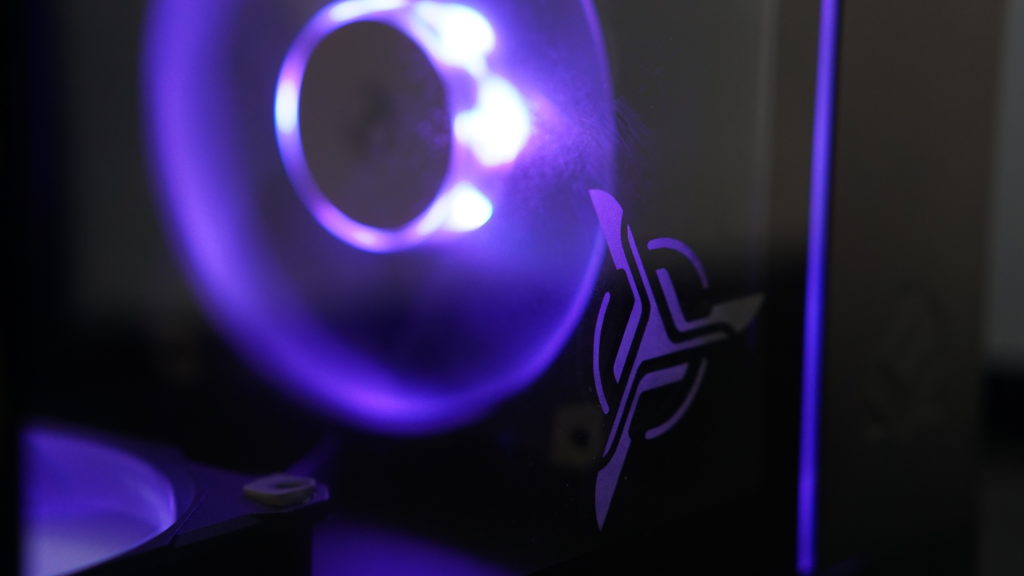 Close-up of a computer with a Skytech Gaming logo etching on the glass and a purple RGB fan visible through the panel. PC hardware.