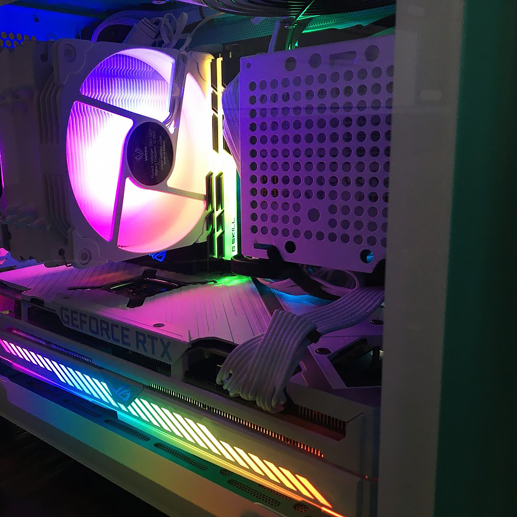 Close up of a computer's internal components: Large white tower cooler and large white 3070 graphics card with 2 sticks RGB RAM and side mounted PSU cage.
