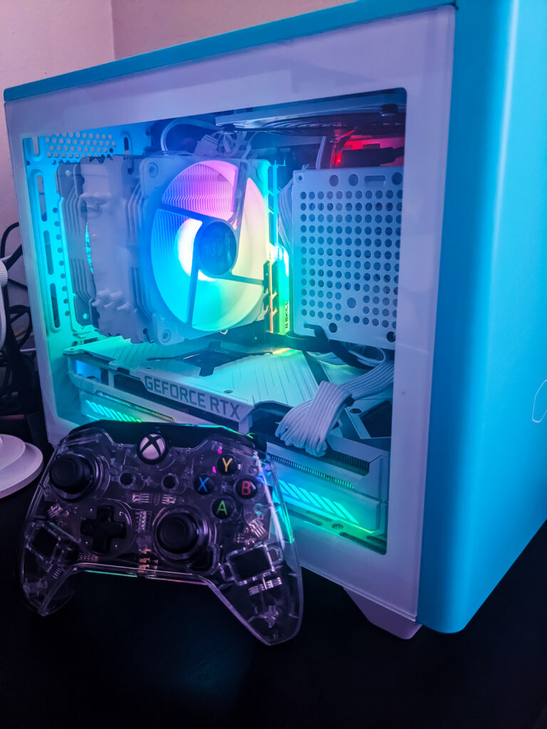 2023 PC game releases. Afterglow Xbox controller leaning on the side glass panel of a teal ITX gaming computer desktop tower.